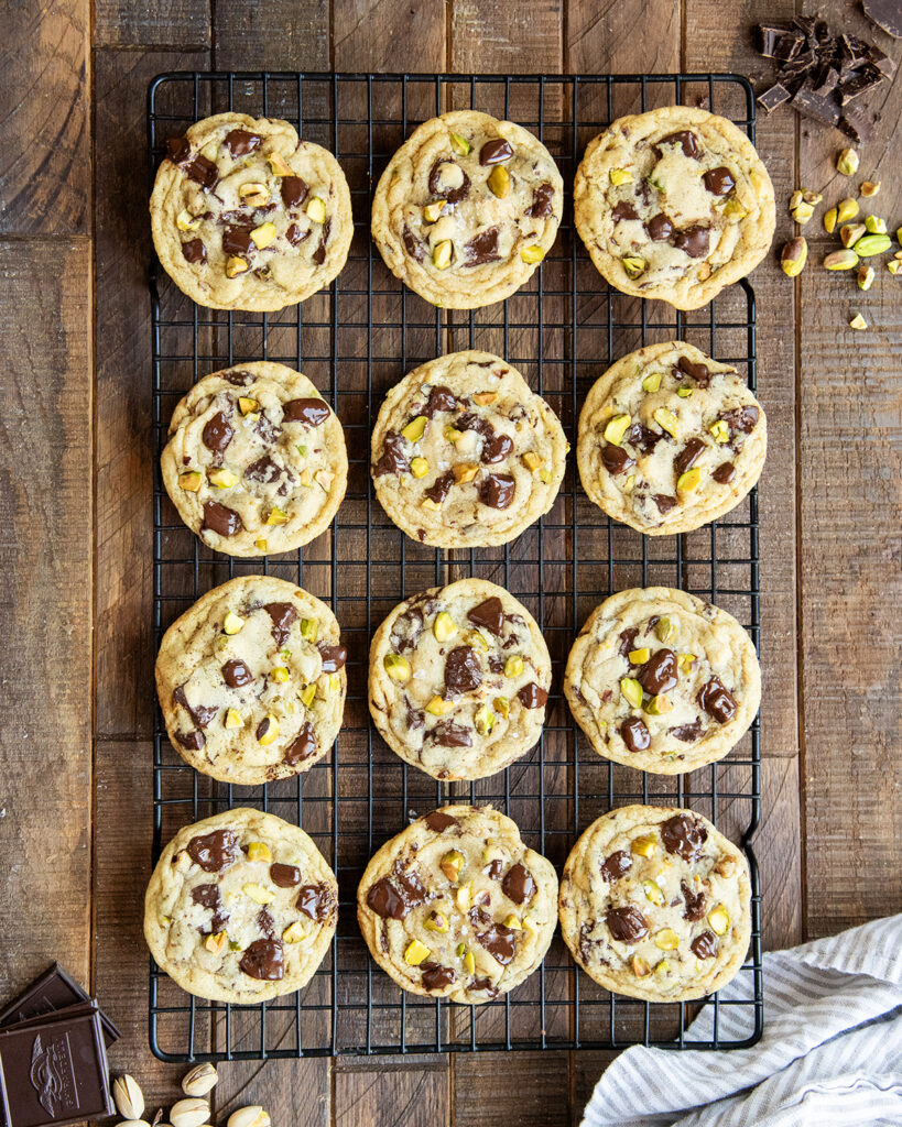 An above view of pistachio chocolate chip cookies on a black wire cooling rack.