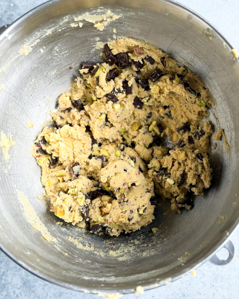 Pistachio and chocolate chip cookie dough in a metal bowl.