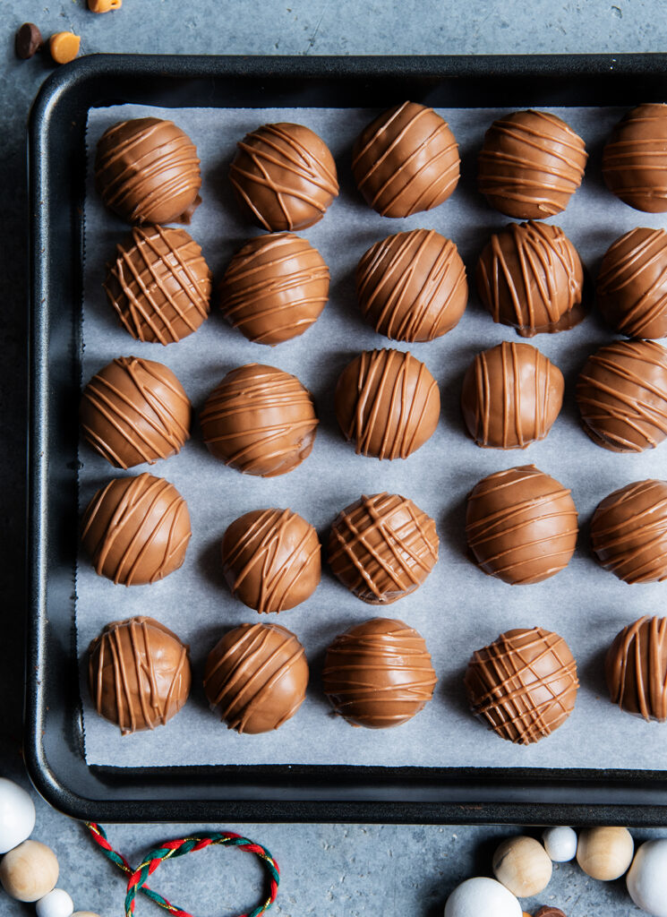 A metal baking tray topped with chocolate scotcheroo balls.
