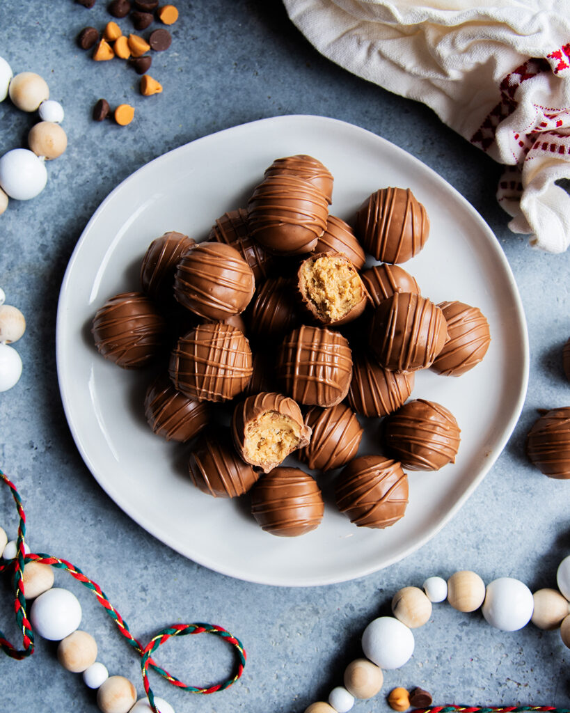 A plate of scotcheroo balls, and two are opened showing the rice crispy peanut butter center.