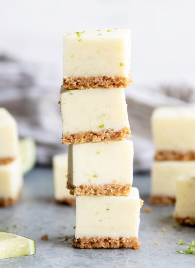 A stack of four pieces of key lime pie fudge, with a graham cracker crust and lime zest pieces in the fudge.