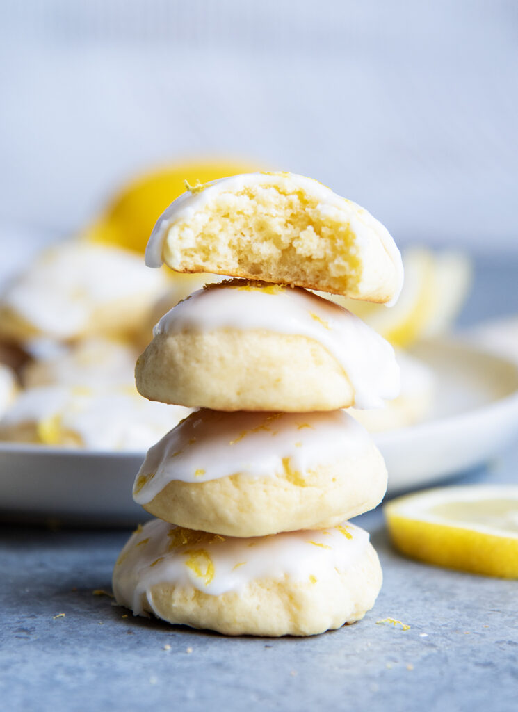 A stack of four iced Italian Ricotta cookies, the top cookie has a bite out of it.