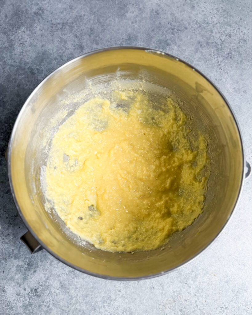 A yellow curdled liquid in a metal bowl, its the wet ingredients to make lemon ricotta cookies.