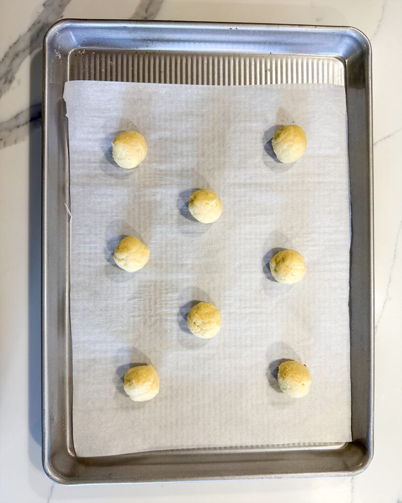 Lemon ricotta cookie dough balls on a cookie sheet.