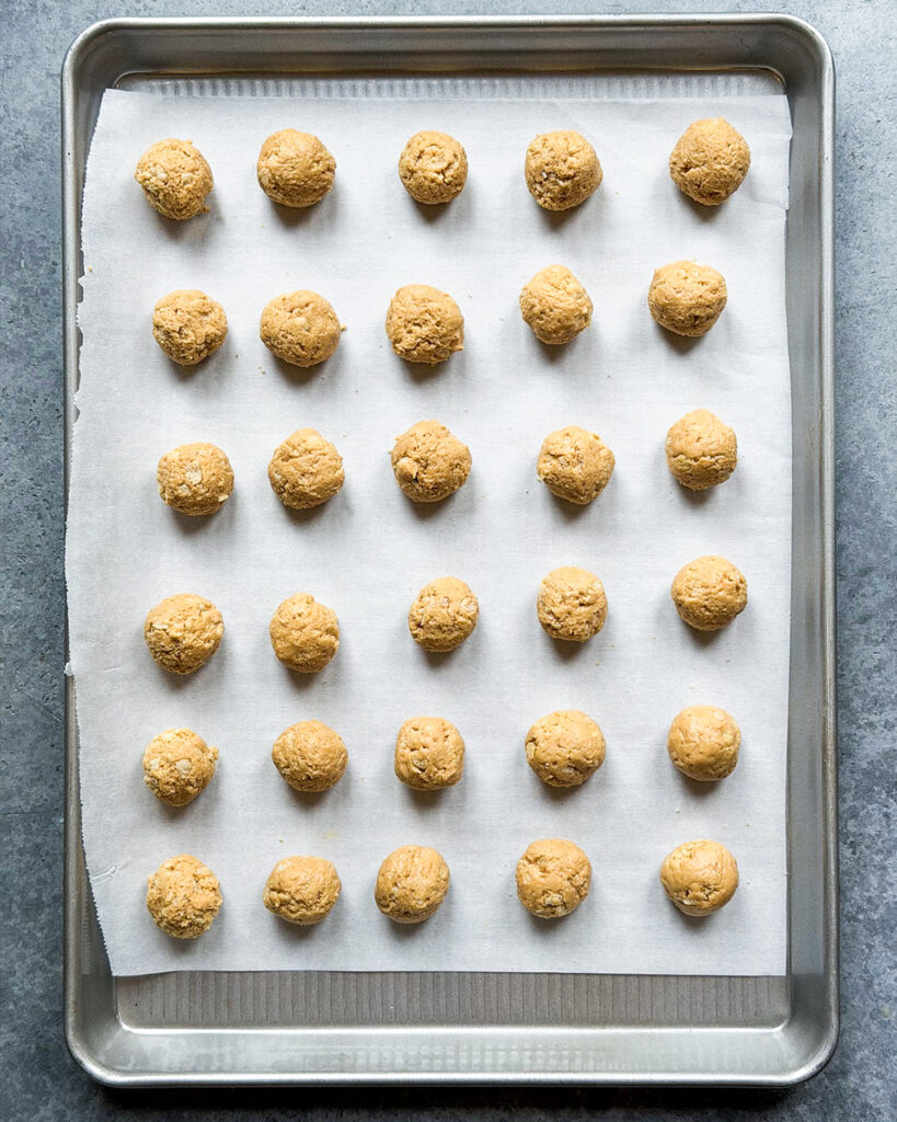 Small peanut butter balls on a cookie sheet.
