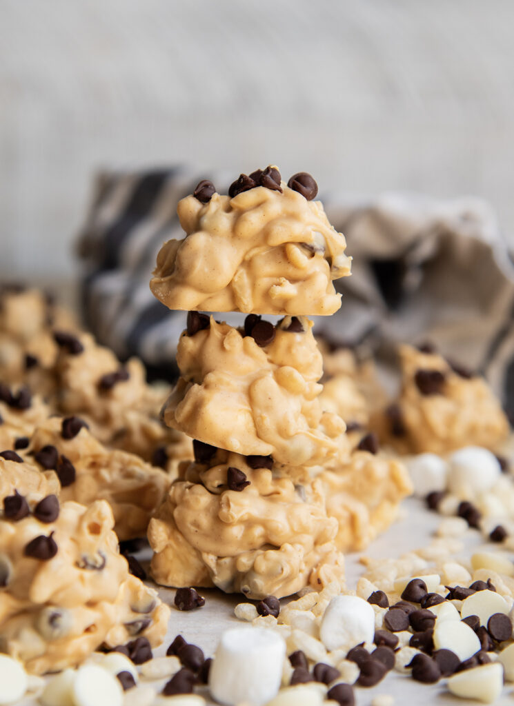 A stack of 3 avalanche cookies that are light orange and brown colored clumps topped with mini chocolate chips.