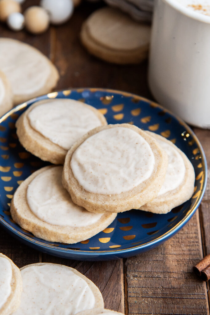 A pile of four vanilla chai cookies on a small blue plate, they are topped with cinnamon vanilla icing.