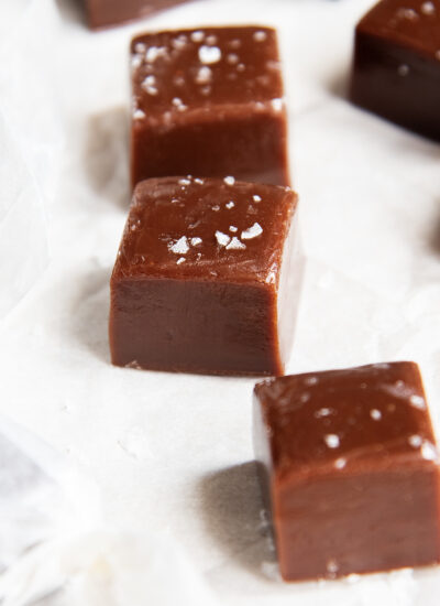 A close up of three chewy chocolate caramels with sea salt on top.
