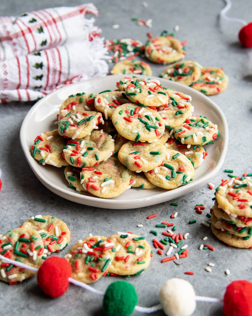 A plate of miniature christmas sprinkle sugar cookies.