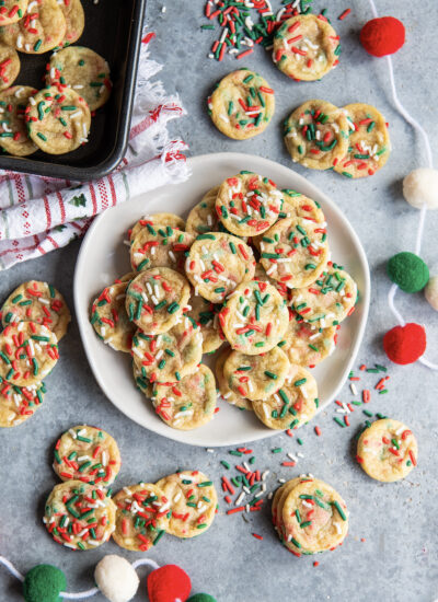 A plate of miniature christmas sprinkle sugar cookies.
