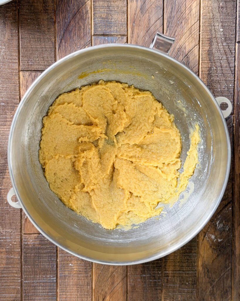 Creamed butter and sugar, mixed with an egg in a mixing bowl.