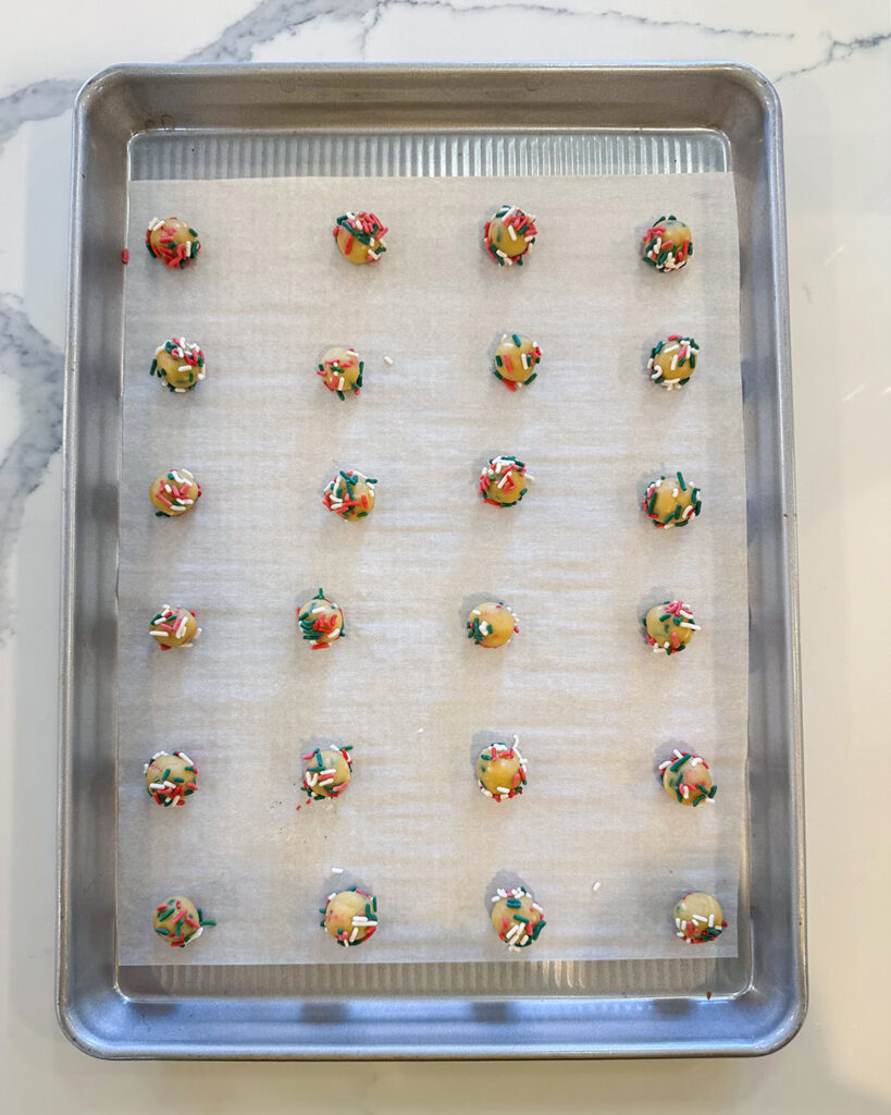 Tiny funfetti cookie dough balls on a baking sheet.