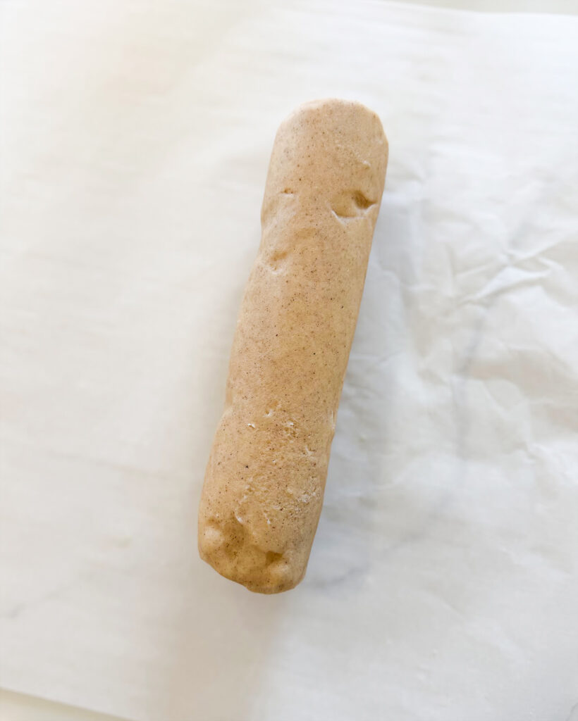 A log of chai shortbread cookie dough on parchment paper.