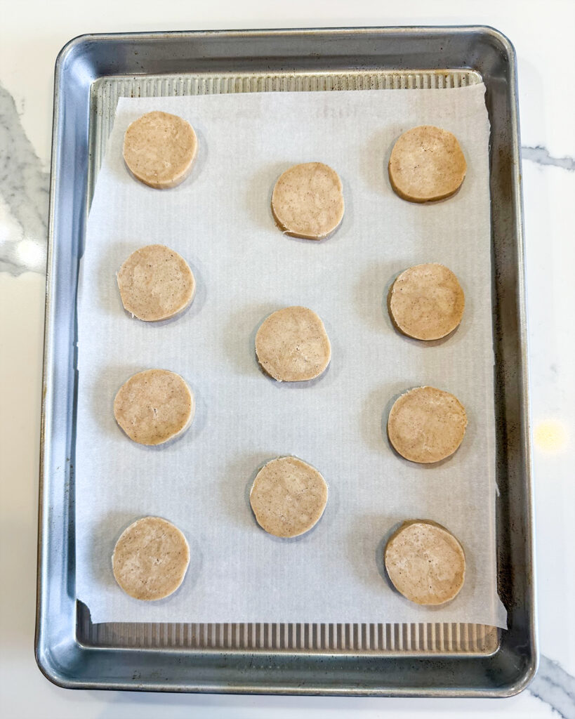 Sliced shortbread cookie dough rounds on a cookie sheet.