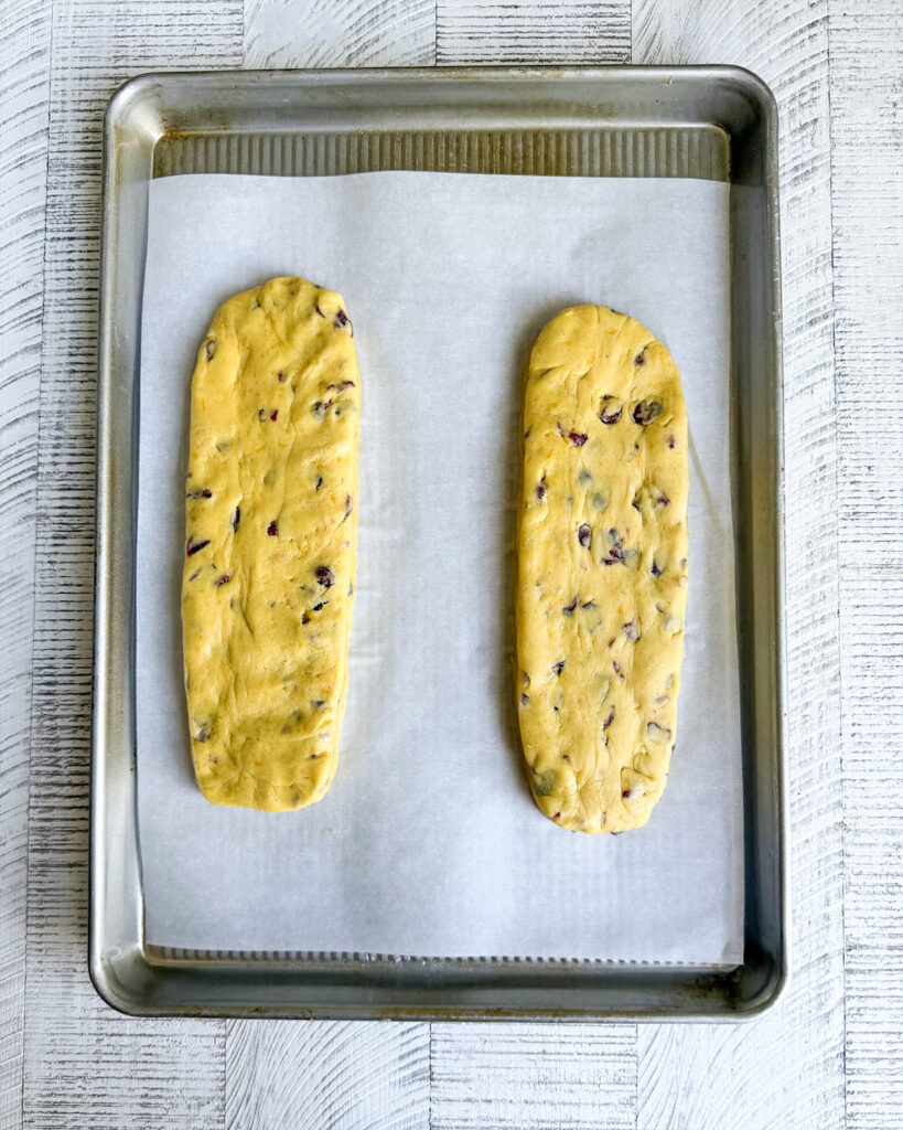 Two loaves of cranberry orange biscotti dough on a cookie sheet.