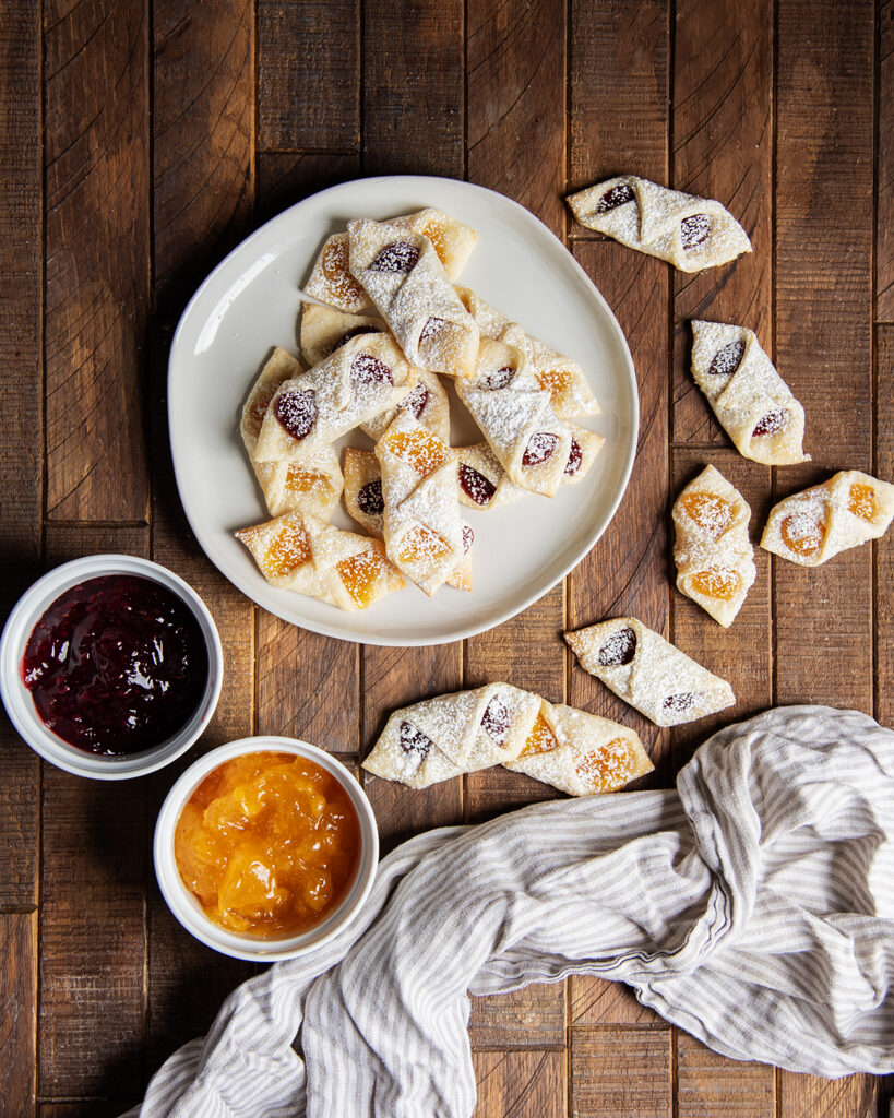 An above view of a plate of kolacky cookies filled with raspberry and apricot jam.