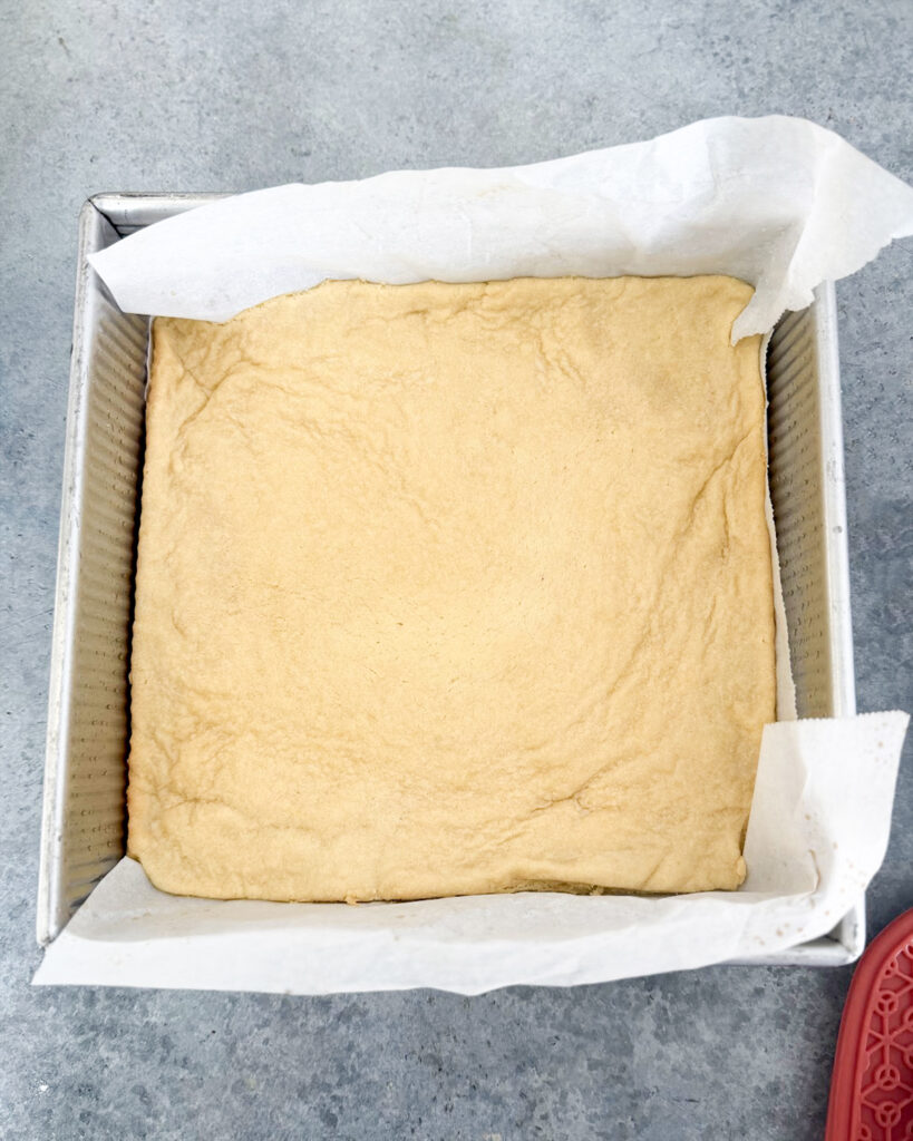A baked layer of shortbread in a square pan.