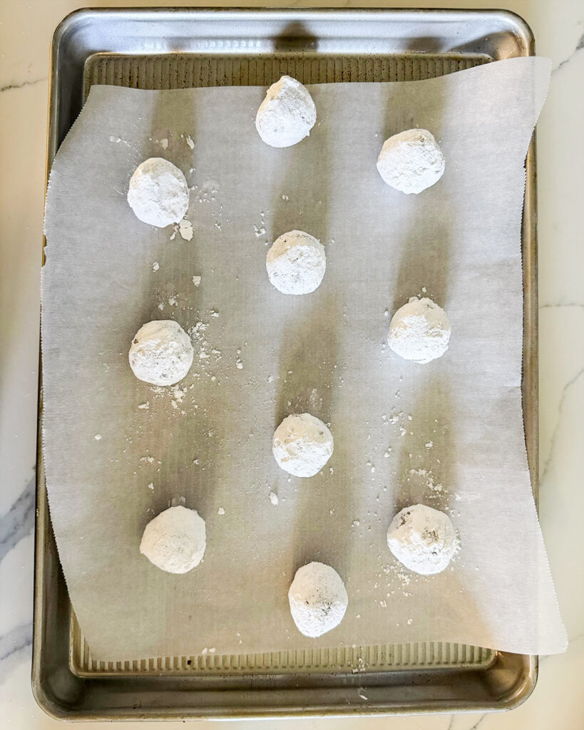 Balls of ginger molasses cookie dough on a cookie sheet.
