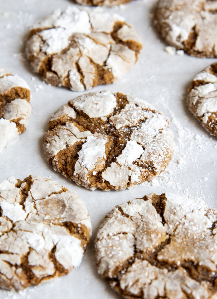 A cookie sheet topped with molasses crinkle cookies, coated in powdered sugar.