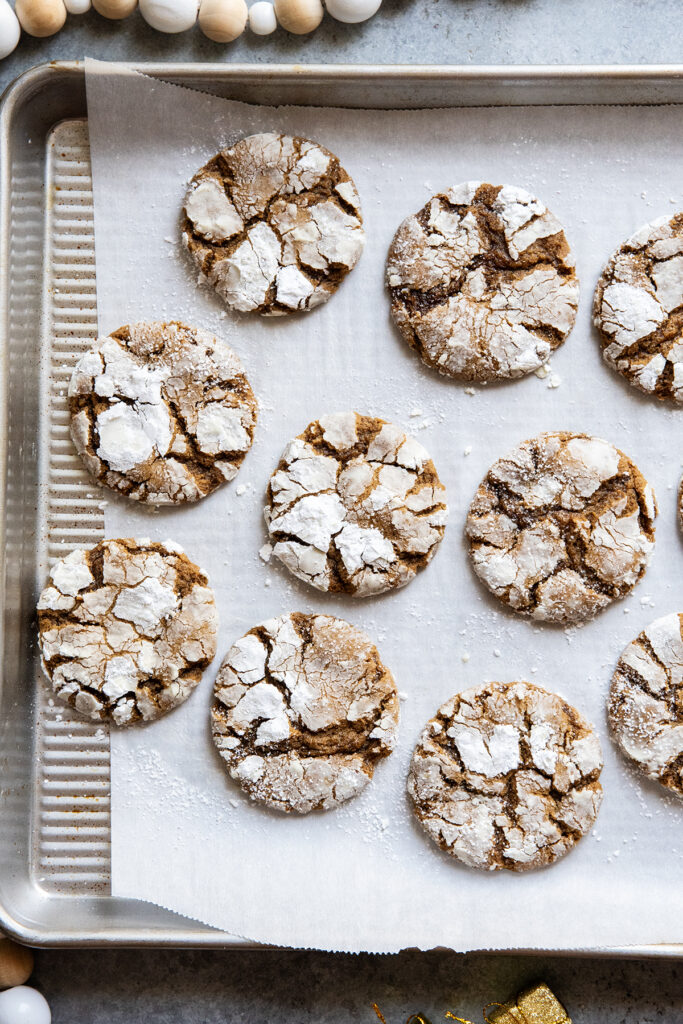 A cookie sheet topped with molasses crinkle cookies, coated in powdered sugar.