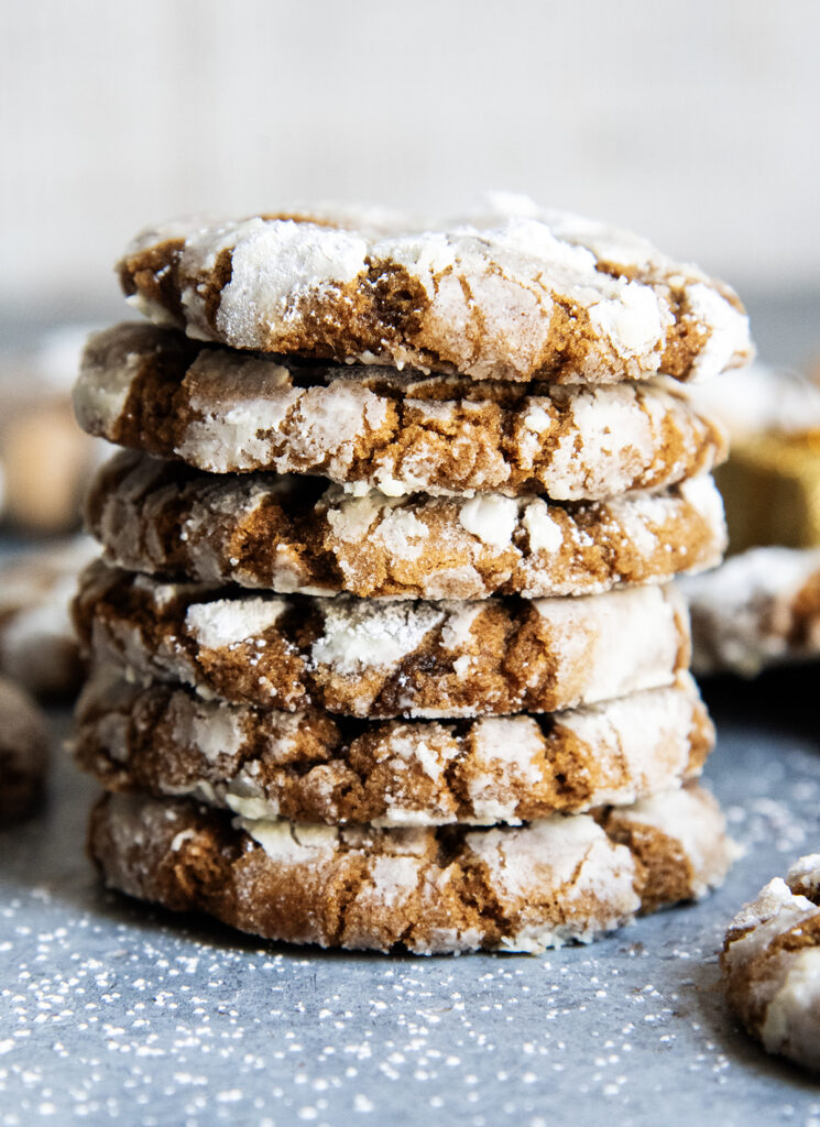 A stack of several ginger molasses crinkle cookies coated in powdered sugar