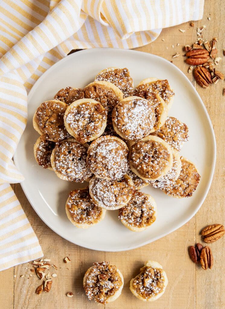 A plate stacked with a pile of pecan tassies on it.
