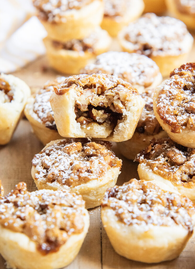 A pile of mini pecan pies, one on top has a bite out of it.