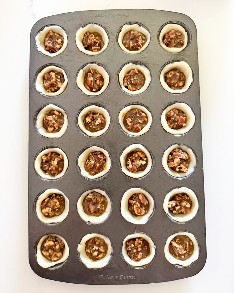 Unbaked pecan tassies in a mini muffin pan.