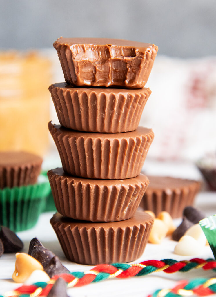 A stack of five chocolate candy cups, the top has a bite out of it.