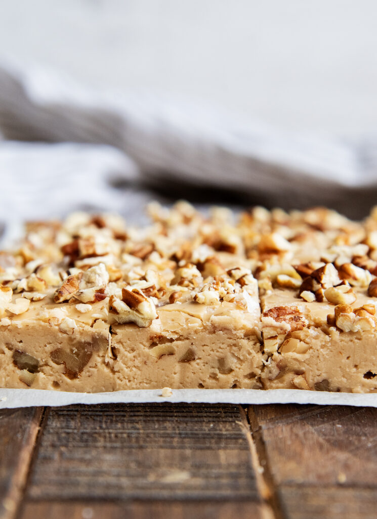 A side view of brown sugar pecan fudge on parchment paper.