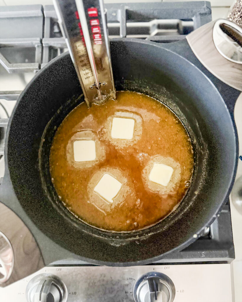 Penuche fudge cooling down with butter slices on top.