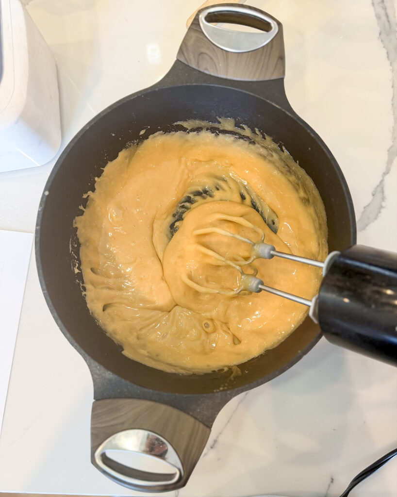 Penuche fudge being beaten with a hand mixer.