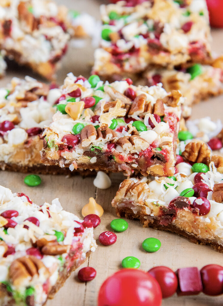 A pile of christmas seven layer bars, they are loaded with coconut and mini christmas m&ms.