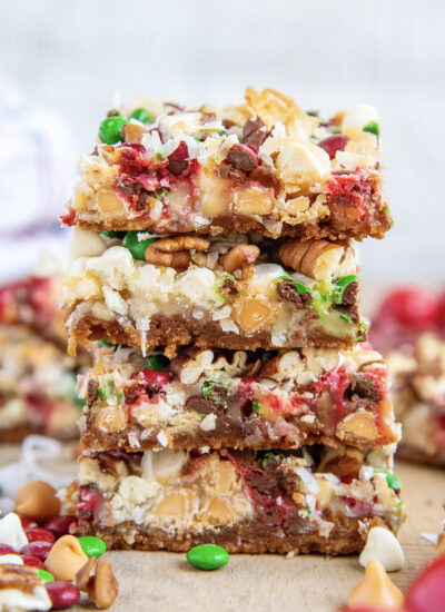 A stack of four Christmas Magic Cookie bars with butterscotch chips, m&ms, and coconut.