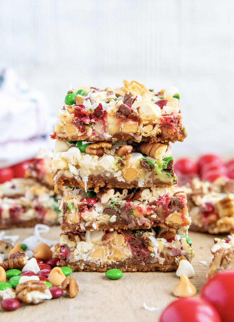 A stack of four Christmas Magic Cookie bars with butterscotch chips, m&ms, and coconut.