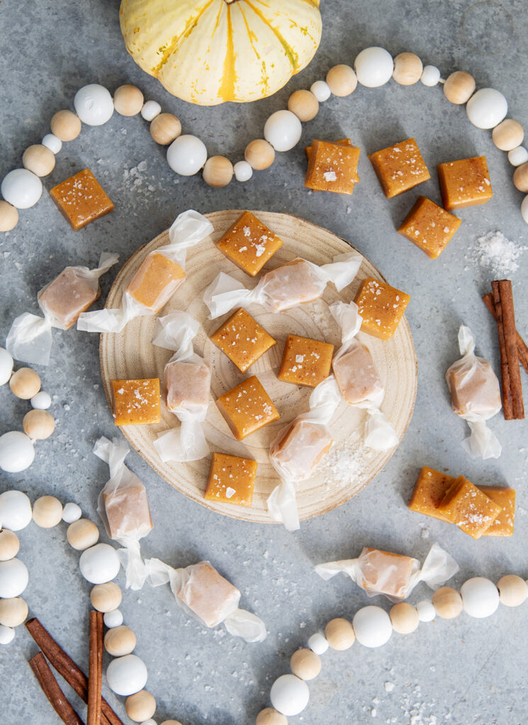 An above view of pumpkin caramels on a wooden board.