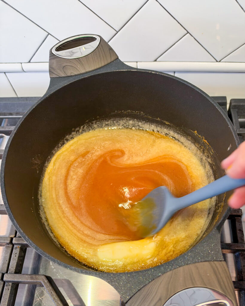An orange colored pumpkin caramel liquid cooking in a pot.