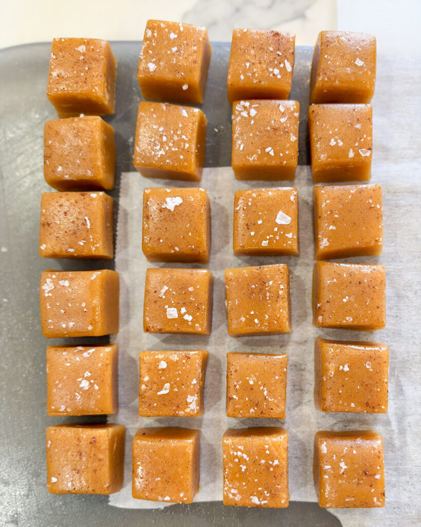 Sliced caramels on a cutting board topped with salt.