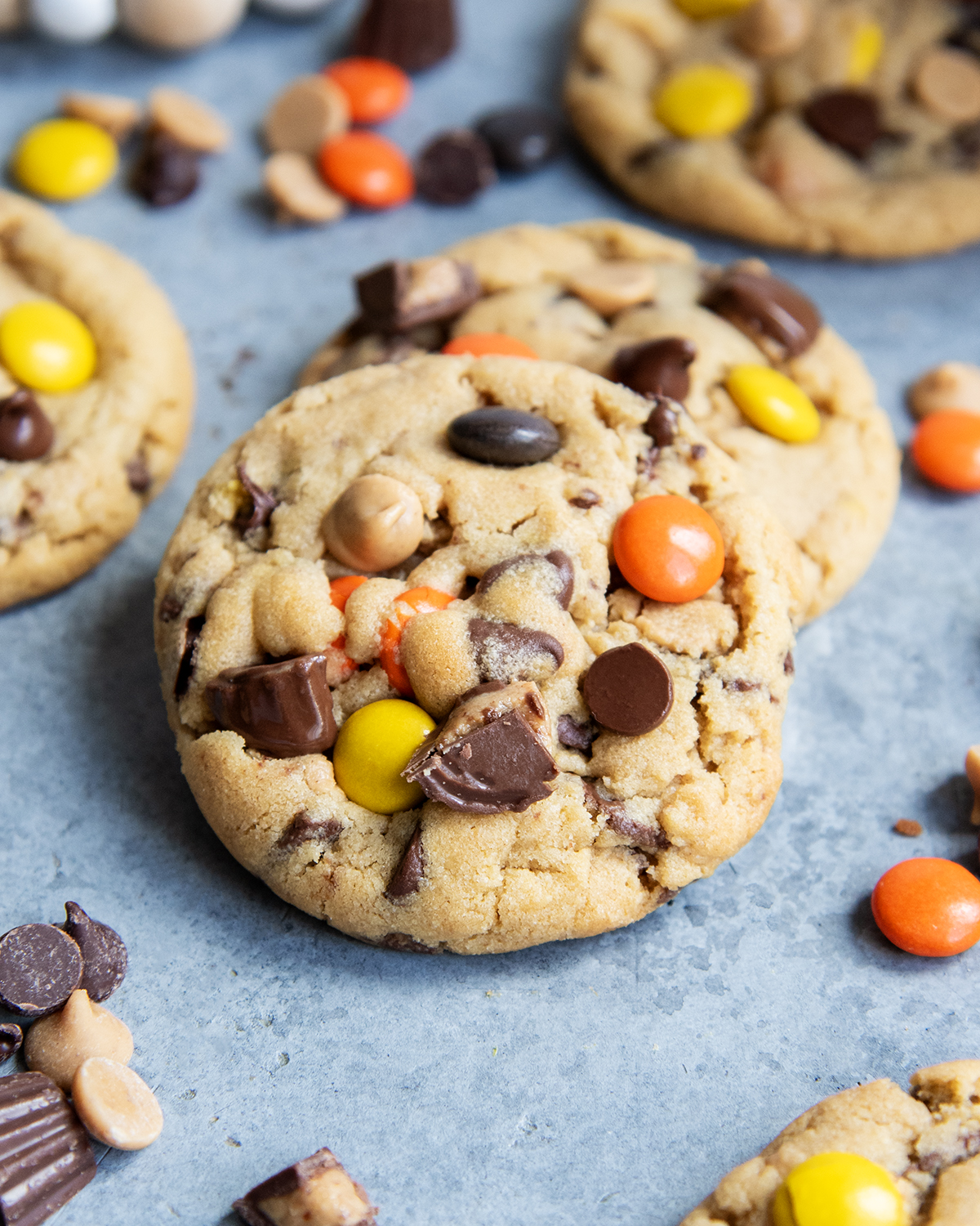 A pile of two peanut butter cookies packed with peanut butter cups and reeses pieces.