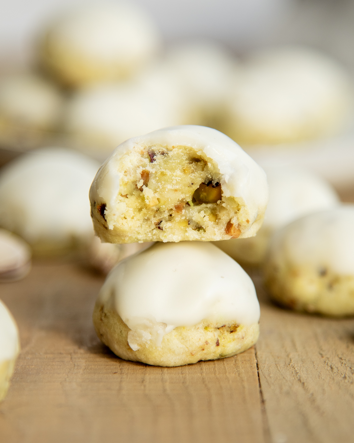 A stack of two pistachio drop cookies, and the top cookie has a bite out of it.