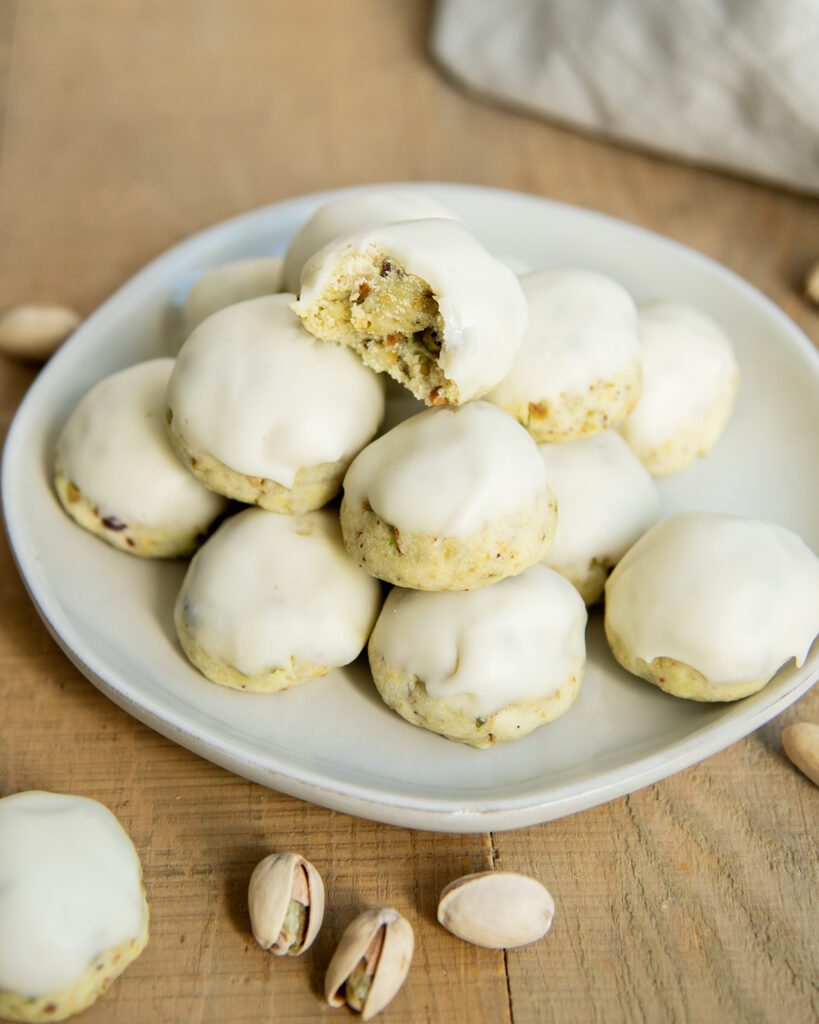A plate of pistachio cookies topped with vanilla icing.