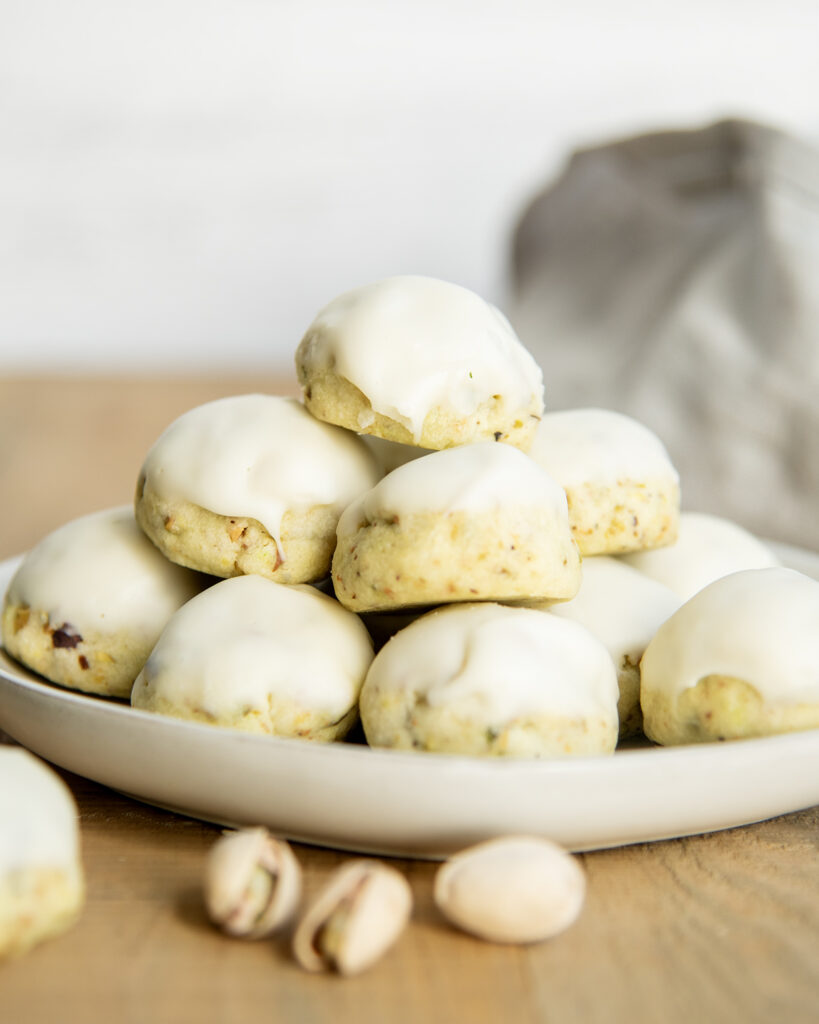 A plate of pistachio cookies topped with vanilla icing.