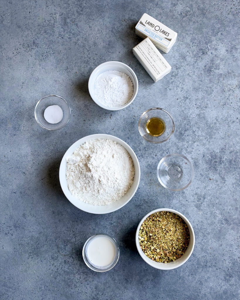 Small bowls of the ingredients needed to make pistachio snowball cookies. 