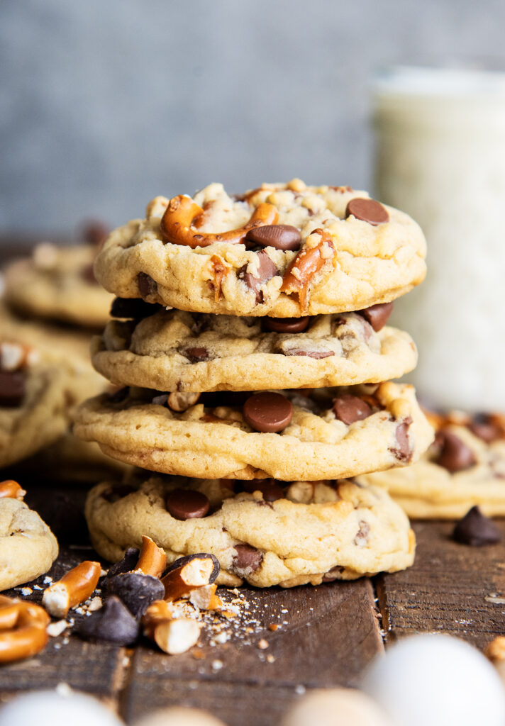 A stack of four drop style cookies filled with chocolate chips and pretzel pieces.